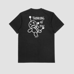 Back view of a black t-shirt featuring a large white graphic of a quirky stitched voodoo doll with pins and the text "Thinking of You".